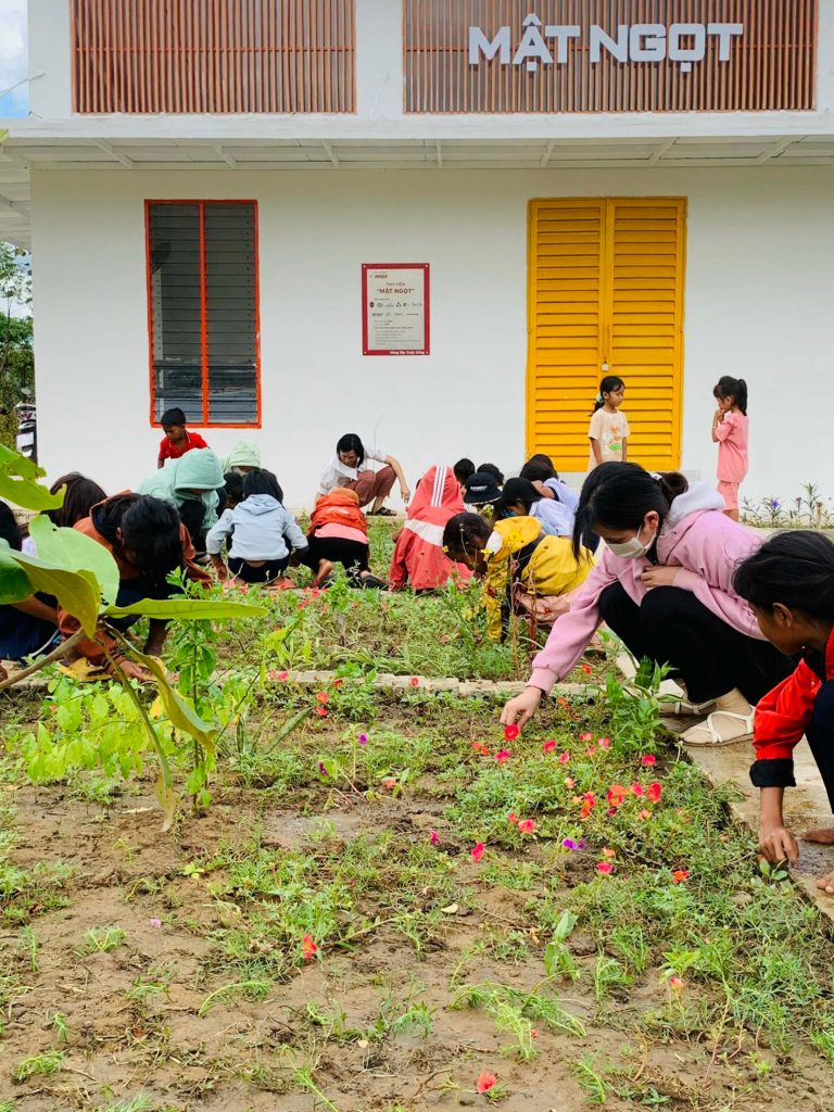 Hình 3: Các em học sinh trường Tiểu học Phước Tân A, huyện Bác Ái, tỉnh Ninh Thuận đang tham gia trồng hoa trước công thư viện Mật Ngọt – Dự án quán quân INSEE Prize 2021 đã được hiện thực hóa. 